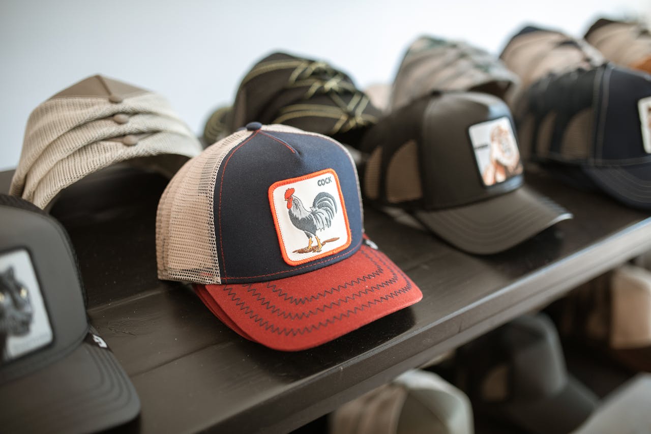 Collection of fashionable graphic caps displayed on a shelf, highlighting unique rooster design.